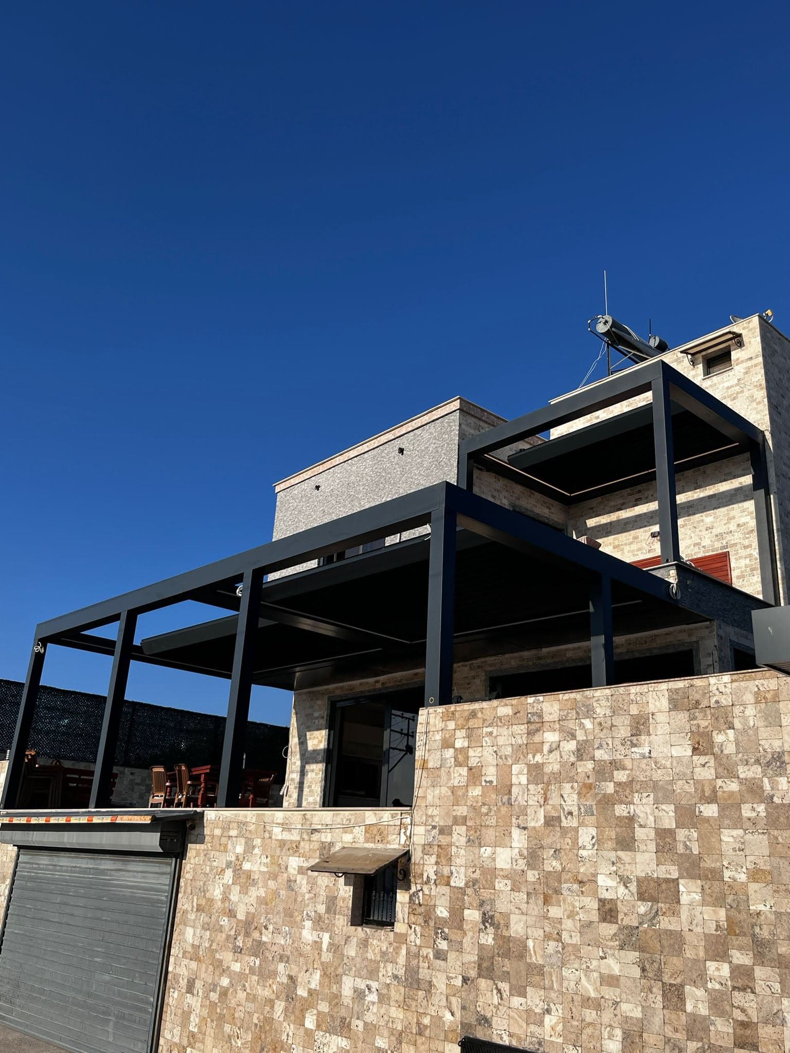 Taş cepheli villanın terasında antrasit bioklimatik pergola